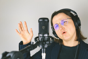 Female caucasian adult singing into microphone with headphones