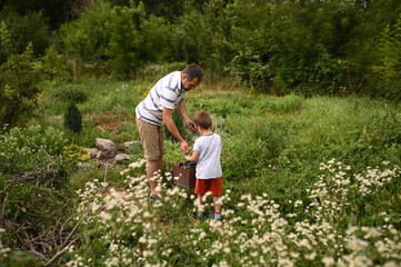 father and son light a fire for barbecue, collect brushwood and put it in the grill in the summer...