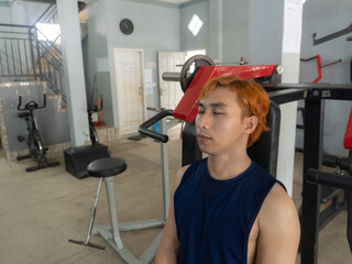 Fitness, breathing and sweat with tired asian indonesian man in the gym, resting after intense...