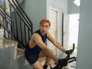 young sports indonesia asian man in blue cycling in fitness center. Cardio workout, leg workout,...