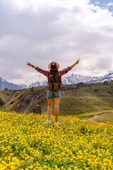 Backpack Flowers Mountain: Hiker with open arms in a meadow enjoys the view during mountain trip.