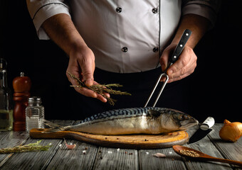 A chef skillfully prepares a fresh mackerel on a wooden cutting board, adding herbs while...
