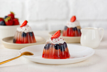 Jelly with fresh strawberry, blueberries and coconut cream on light table. Healthy food, vegan, sugar, gelatin and lactose free.