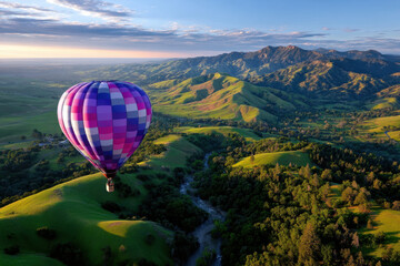 Colorful hot air balloon gliding over lush green hills during sunrise