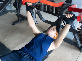 Asian men use gym equipment to do tricep, chest, arm exercises, focusing on building strength and maintaining a healthy lifestyle. Upper body strength training
