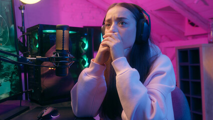 Frustrated sad woman gamer girl female streamer in headphones worry upset with fail loss bad result failure at computer online game playing in neon home room at night addiction gaming problem stream © Yuliia