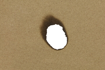 A burnt paper hole with charred edges on brown paper. This grunge texture creates a dramatic...