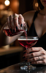 Bartender pouring red cocktail in a glass