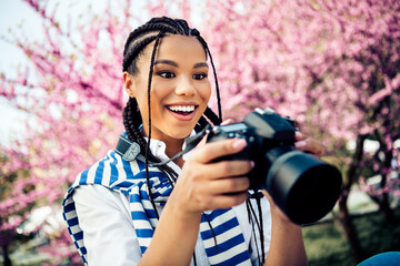 Cute woman with camera enjoying a spring day surrounded by pink blossoms capturing moments of joy and beauty outdoors