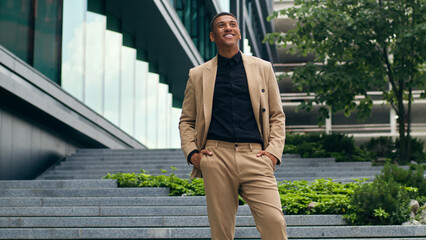 Happy successful excited employer ethnic entrepreneur near office building company walk African...