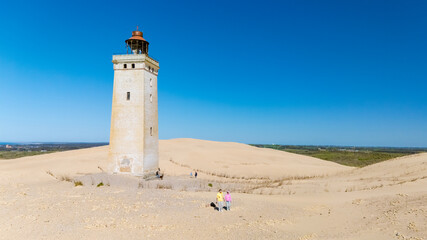 Dramatic views of a historic lighthouse amid golden sands in the Danish landscape
