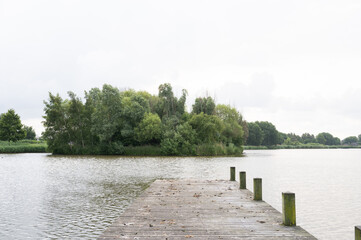 Serene lake view with wooden pier and lush green island in tranquil landscape
