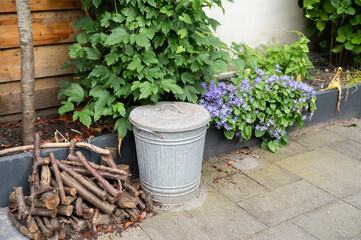 Galvanized metal bin and branches in garden with purple flowers