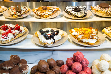 Assorted gourmet waffles with diverse toppings displayed on plates in bakery setting