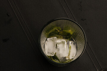 glass of mojito with ice and mint and droplets on black background in an Italian bar during summer 2025