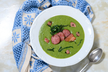Delicious homemade green soup with sausage and cabbage in a white dish