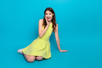 Charming young woman in a vibrant yellow dress on blue background sharing a moment of joy and style