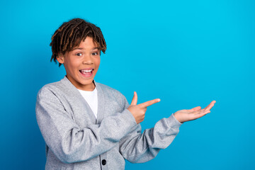 Smiling Schoolboy in Gray Cardigan Gesturing Enthusiastically Against Blue Background