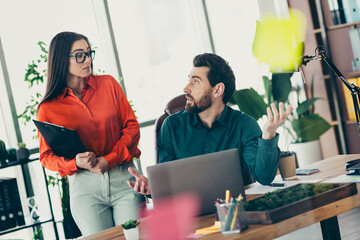 Professional coworkers discussing strategy in a modern office setting surrounded by plants and...