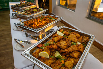 Fish fried in batter in a metal dish at a buffet station