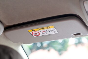 A sun visor in a car with airbag safety sticker label