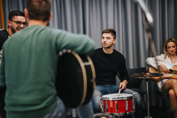 A group of musicians gathers in a studio, enthusiastically playing instruments and collaborating to...