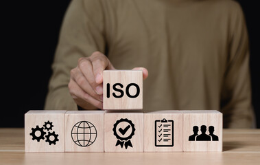 Businessman holding a wooden cube ISO standards quality control, assurance warranty business,...