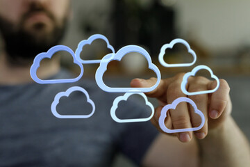 A person interacts with holographic cloud icons, symbolizing data storage and cloud computing.