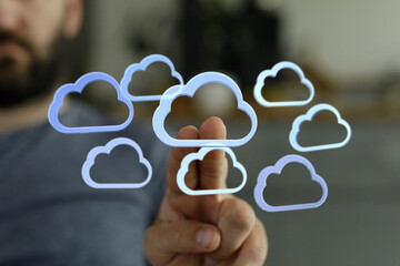 Person interacts with cloud icons, symbolizing cloud computing, data storage, and digital...