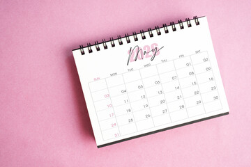 Top view of May 2026 desk calendar on pink pastel background.