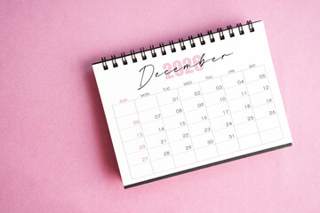 Top view of December 2026 desk calendar on pink pastel background.