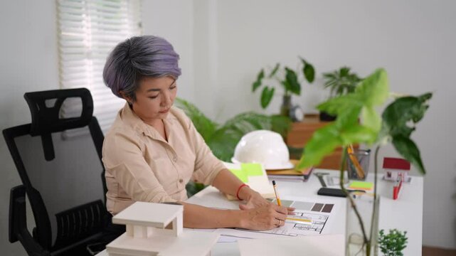Architect woman drafting technical designs with scale ruler and model building in office space