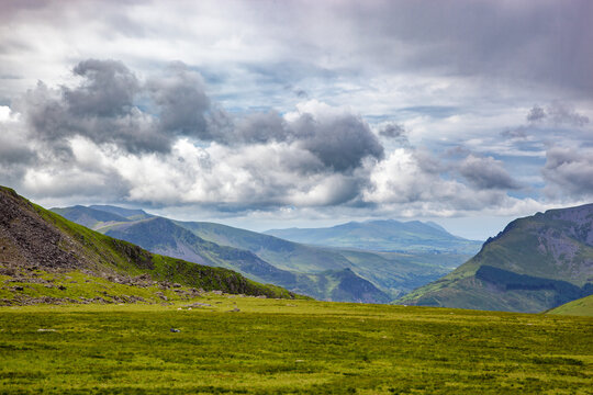 A panoramic view of the mountains and valley of North Wales. Summer day with low clouds and the lush green grass of the Welsh countryside.
