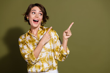 Young businesswoman with brunette hair wearing stylish blouse points happily against khaki...