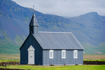 Stunning black church surrounded by Icelands majestic mountains on a cloudy day