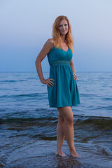 Beauty young woman walking on sea coast in blue dress. Cyprus island, blue hour