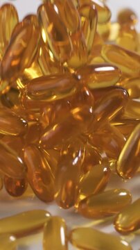 Vitamins and supplements fall onto a table in slow motion. Vertical Video.