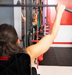 Close up of sportswoman exercising back muscles using training apparatus in gym