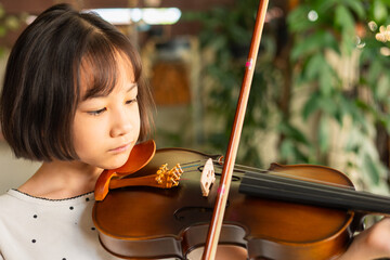 Asian girl passionately plays the violin, demonstrating focus and dedication during a music lesson....