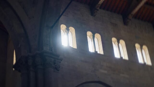 Sunlight beam shining through dark church or cathedral window creating flare. Old ancient historic place of worship or temple with arched windows where sun strongly brightly shines in god like rays