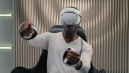 Futurism gaming internet video game virtual reality African American man male guy in vr glasses helmet playing 3d world in white futuristic room indoors modern online having fun enjoy play metaverse