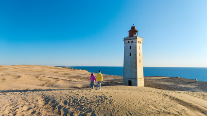 Explore the iconic lighthouse of Rubjerg Knude on the sandy coastline in Denmark during sunset