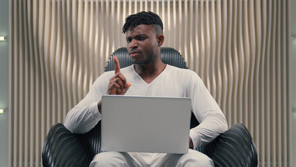 African American man gamer programmer student businessman business male guy laptop using internet online gaming modern futuristic room showing no not never gesture finger shake deny refuse forbidden