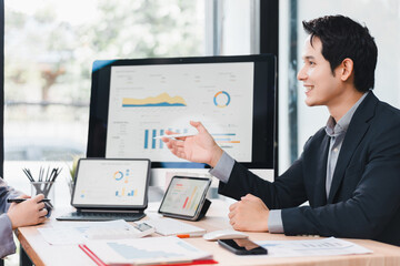 Businessman suit office meeting digital tablet computer chart graph report teamwork discussing smiling professional technology workspace data analysis finance planning modern Asian male corporate