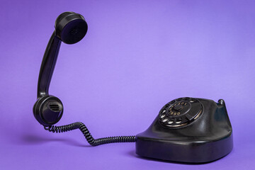 Vintage Black Rotary Dial Telephone with Handset Off the Hook on Purple Background. Retro...