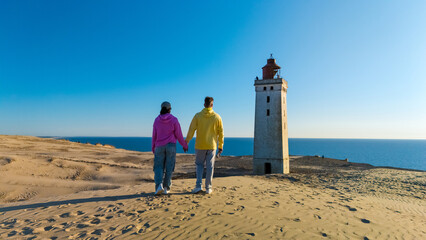 Couple holding hands with a lighthouse view in Denmark on a sunny day