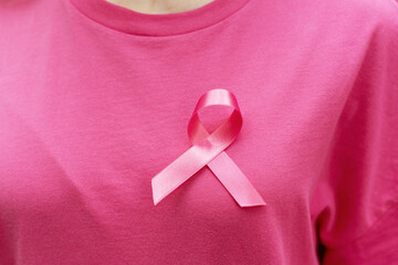 Woman wearing pink ribbon on shirt supporting breast cancer awareness