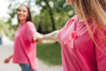 Women holding hands wearing pink ribbon for breast cancer awareness
