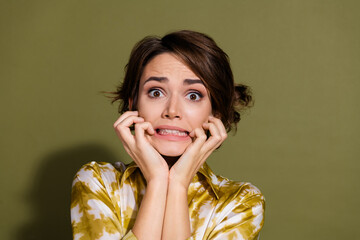 Worried young businesswoman with brunette hair in khaki background, expressing anxiety in elegant...