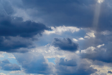 Bright sun rays fall on a dense layer of clouds in the sky, sun rays among clouds in the sky.